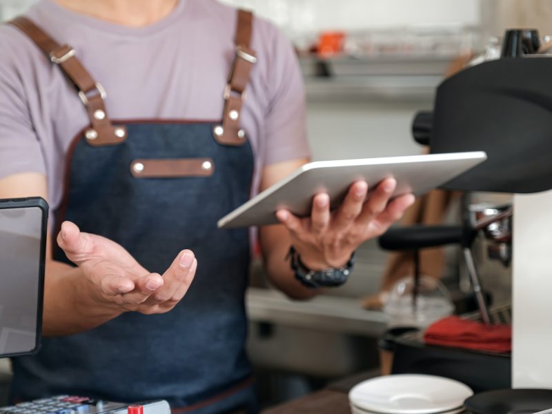 barista holding a tablet in hand, recommending menu and receiving orders from customers.
